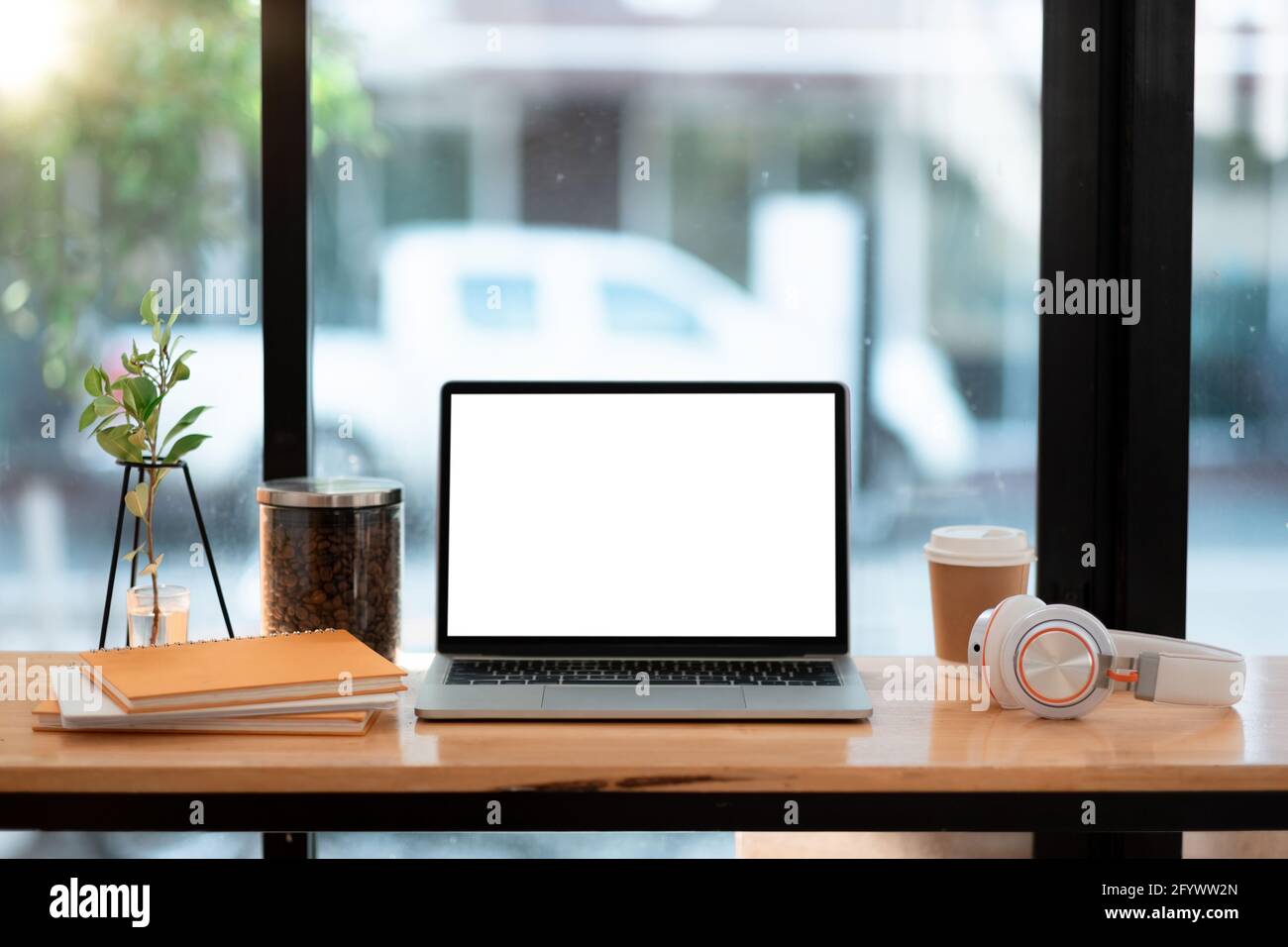 Laptop-Computer mit leerem weißen Bildschirm und Kaffee, Buch auf dem Kaffeetisch Stockfoto