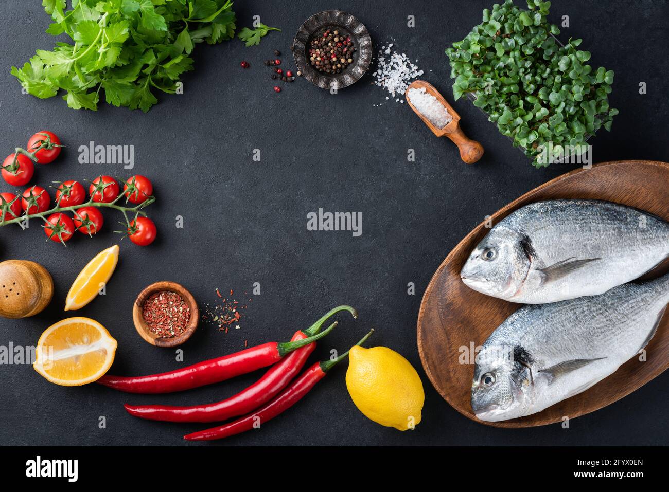 Food Frame ungekochte Fische und Zutaten Gemüse, Gewürze und Gemüse auf schwarzem Schiefer Hintergrund, Draufsicht, Kopierraum. Gesundes Kochen Stockfoto
