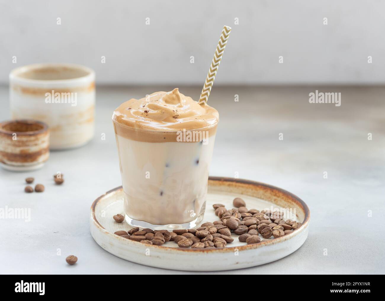 Dalgona Kaffee mit süßem Schaum und Eis in einem Glas mit Stroh. Schlagkaffee. Grauer Hintergrund. Horizontales Bild. Platz für Text. Stockfoto