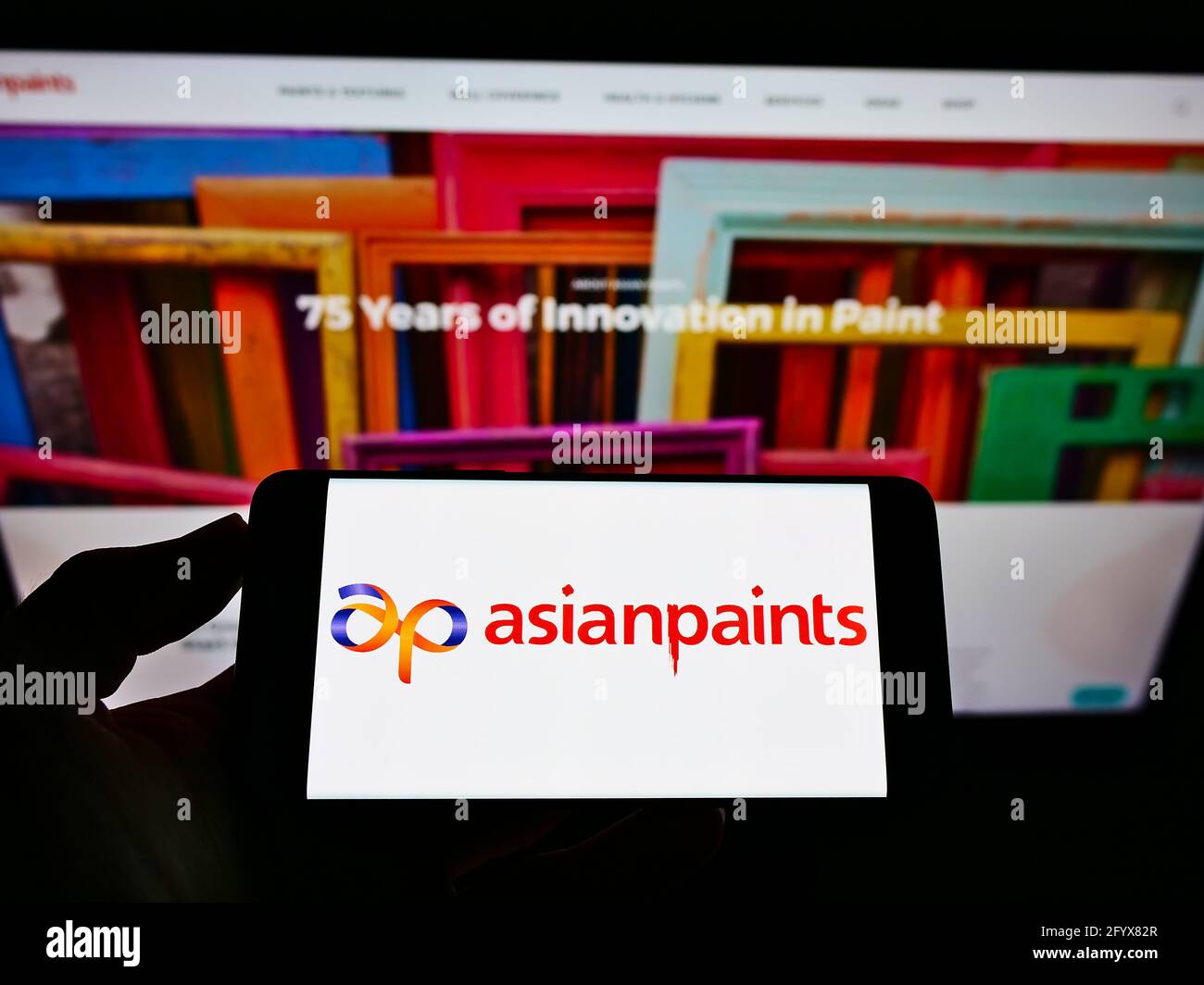 Person, die das Smartphone mit dem Logo des indischen Chemieunternehmens Asian Paints Ltd. Auf dem Bildschirm vor der Website hält. Konzentrieren Sie sich auf die Telefonanzeige. Stockfoto