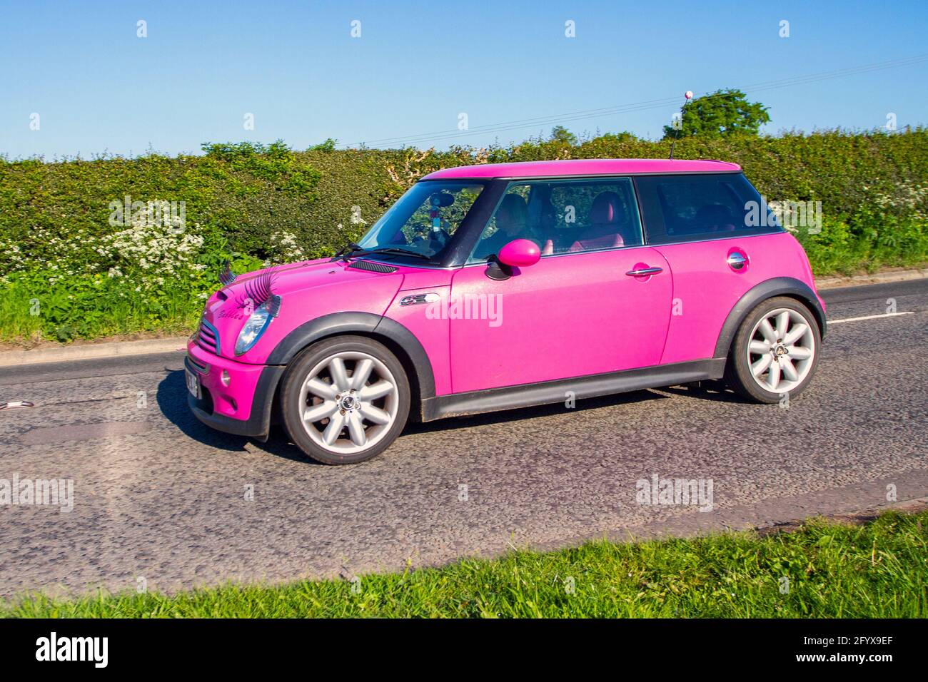 2004 pink Mini Cooper S, mit Augenbrauen auf den Scheinwerfern; Fahrzeugverkehr, bewegliche Fahrzeuge, Autos, Fahrzeuge, die auf britischen Straßen fahren, Motoren, auf dem Weg zur Capesthorne Hall classic May Car Show, Ceshire, UK Stockfoto
