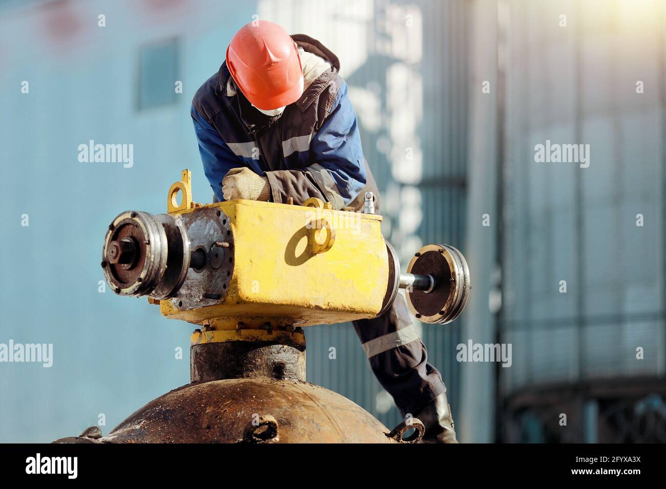 Ein Mann in Arbeitskleidung und einem Hut arbeitet im Winter mit Gasgeräten im Freien. Reparatur des Linearkrans der Hauptgasleitung. Stockfoto