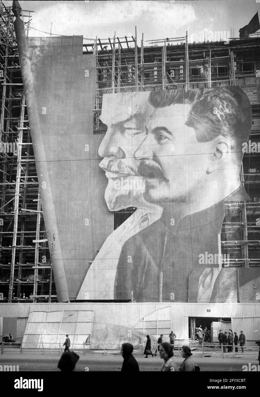 Ein großes Plakat mit Porträts der russischen politischen Führer Wladimir Lenin und Joseph Stalin für die Parade zum 1. Mai hängt über dem Gerüst eines Gebäudes im Bau, Moskau, Russland, 1934. (Foto von Burton Holmes) Stockfoto