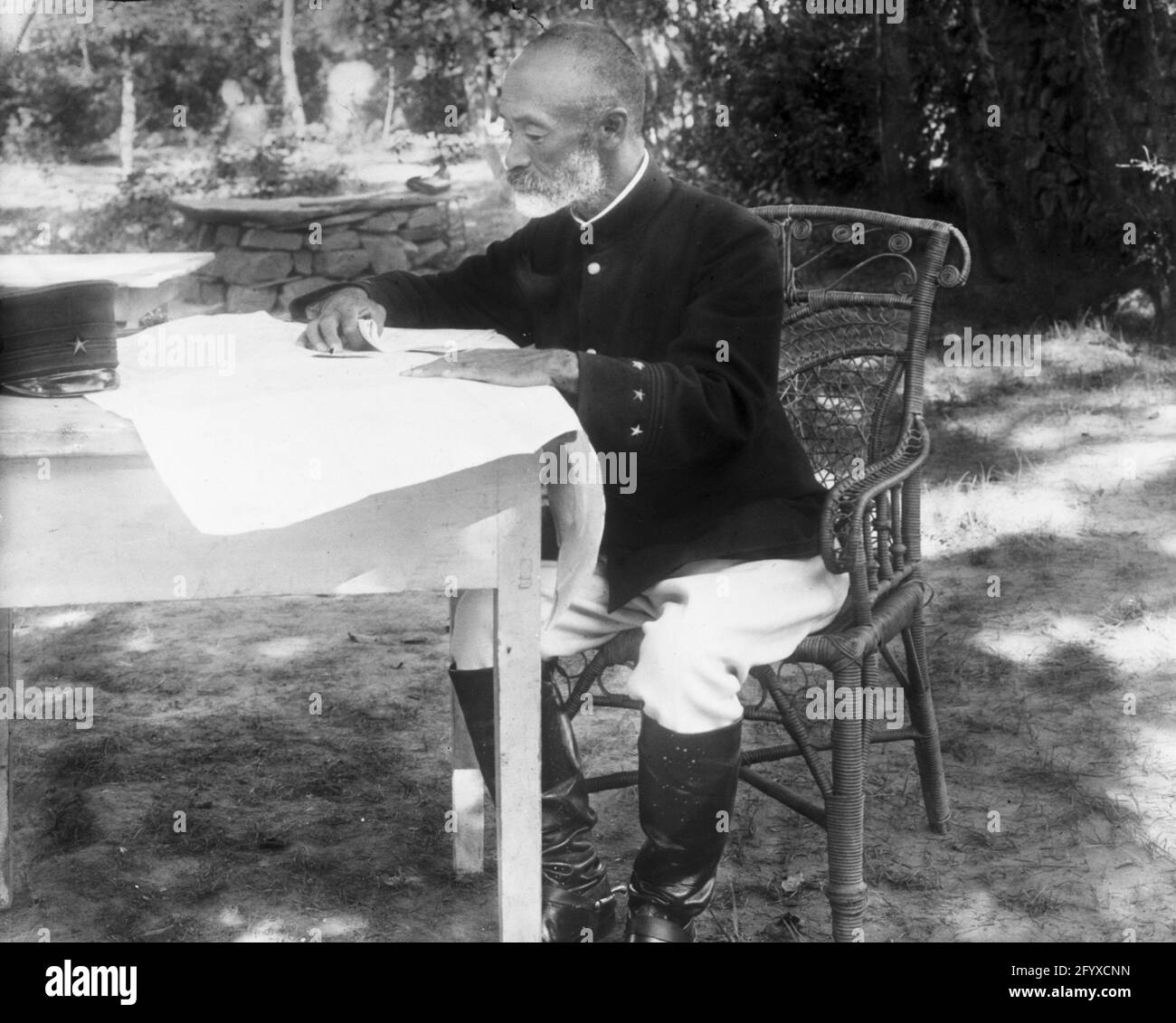 Der japanische General Graf Nogi Maresuke (1849 - 1912) saß an einem Tisch und studierte eine Karte im japanischen Hauptquartier während des Russisch-Japanischen Krieges, Port Arthur, China, 1904. (Foto von Burton Holmes) Stockfoto