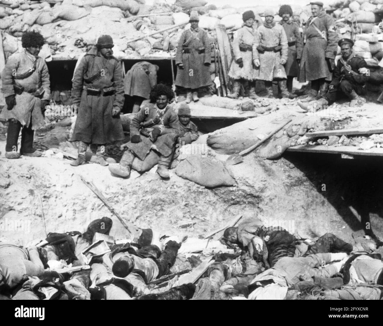 Russische Soldaten, die während des Russisch-Japanischen Krieges 1905 in einem Graben über den Leichen toter japanischer Soldaten standen. (Foto von Burton Holmes) Stockfoto