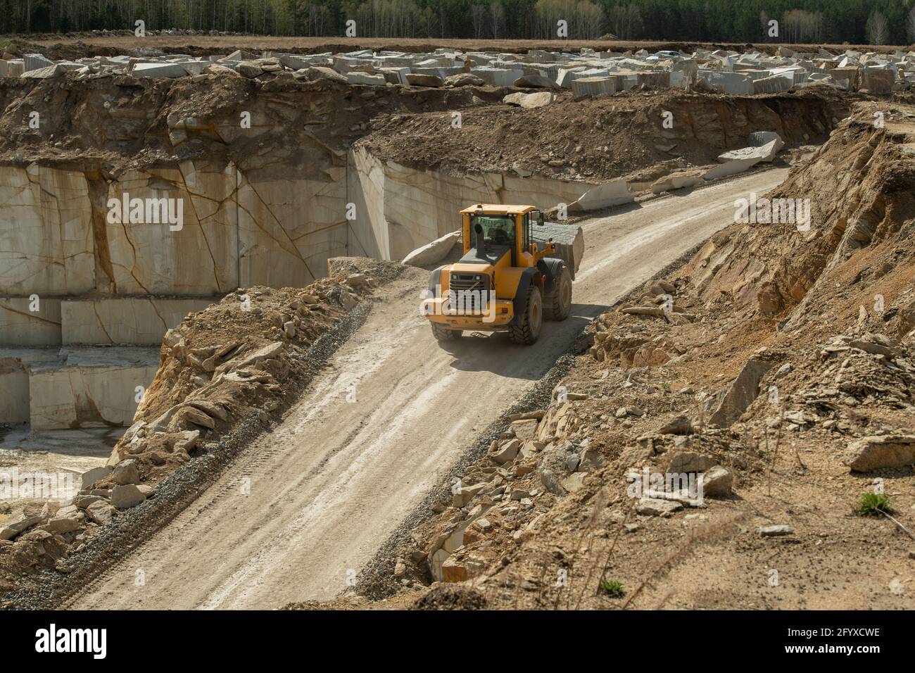 Traktor fährt auf einer schmalen Straße, umgeben von Baustellen und Hölzer Stockfoto