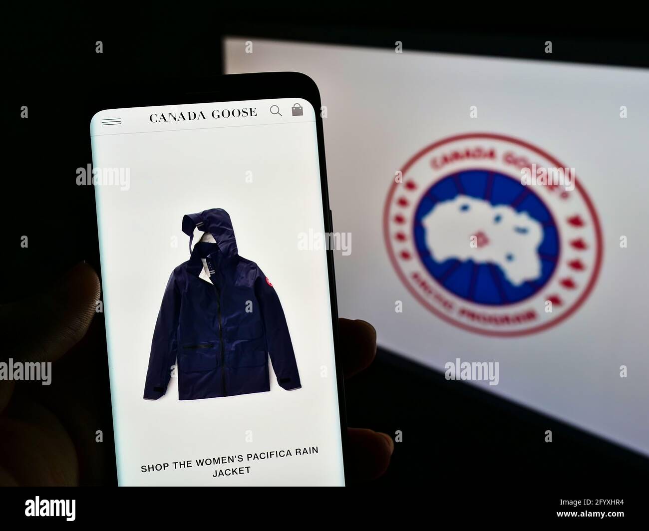 Person mit Mobiltelefon auf der Website des Winterbekleidungsunternehmens Canada Goose Holdings Inc. Auf dem Bildschirm mit Logo. Konzentrieren Sie sich auf die Mitte des Telefondisplays. Stockfoto