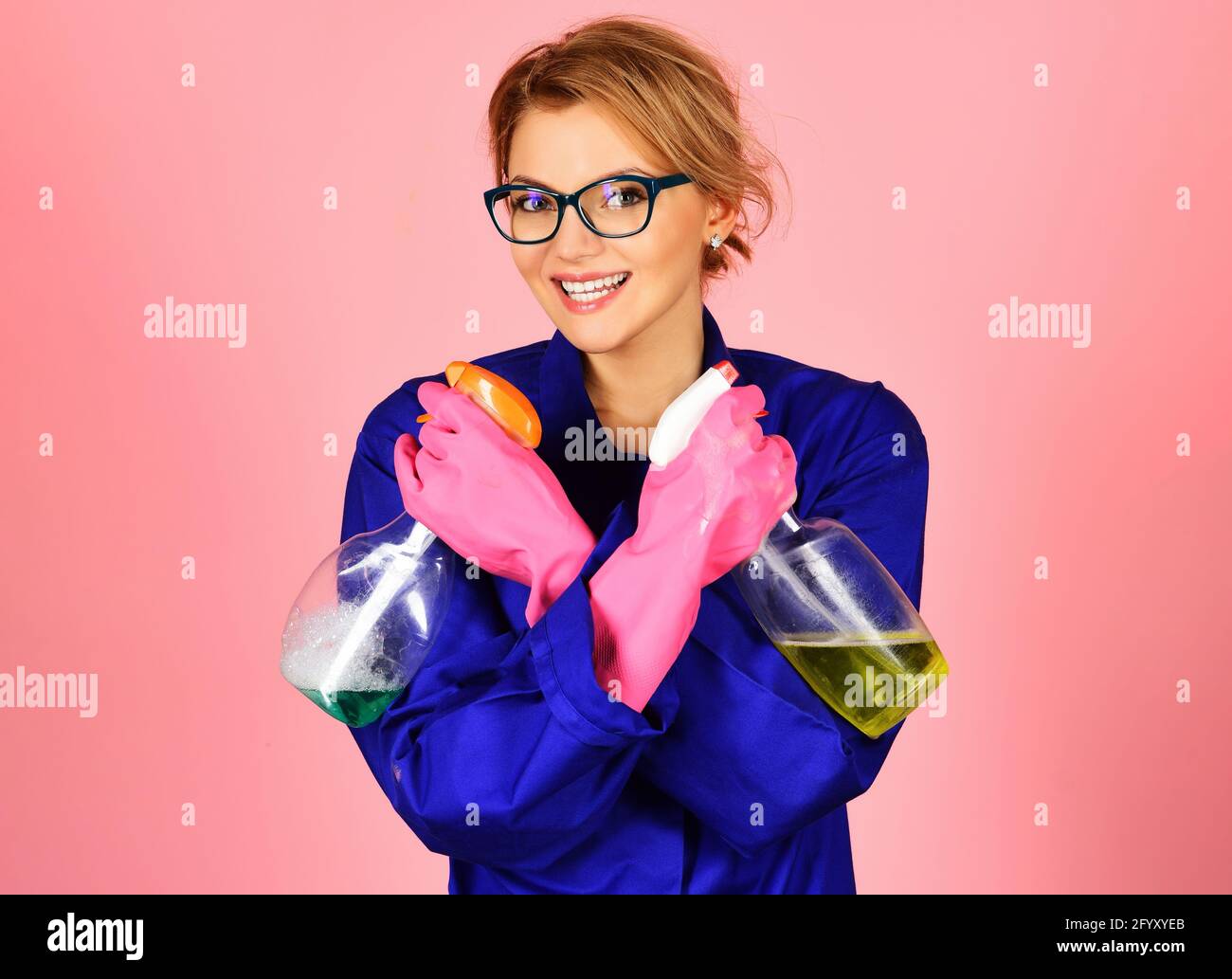 Glückliche Frau in Uniform und Gummihandschuhen mit Reinigungsspray. Professioneller Reinigungsservice. Stockfoto