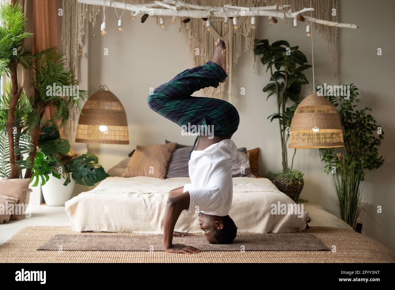 Junger afrikanischer Fitnesssportler in Yoga-Position am Kopf arbeiten Stockfoto