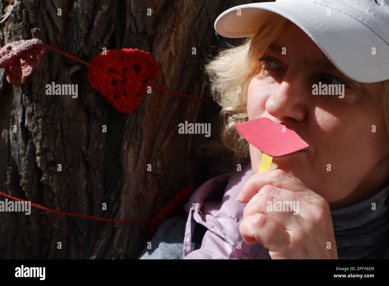 Eine Frau mit Herzkranzen hält Papierlippen und ein Herz als Symbol der Liebe. Welt-Kuss-Tag. Stockfoto