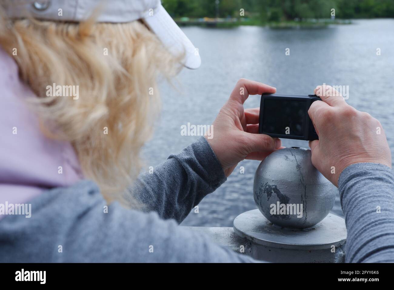 Ein Mädchen mit weißer Mütze fotografiert mit einer Kamera die Wasserlandschaft. St. Veronica's Day Photographer's Day . Stockfoto