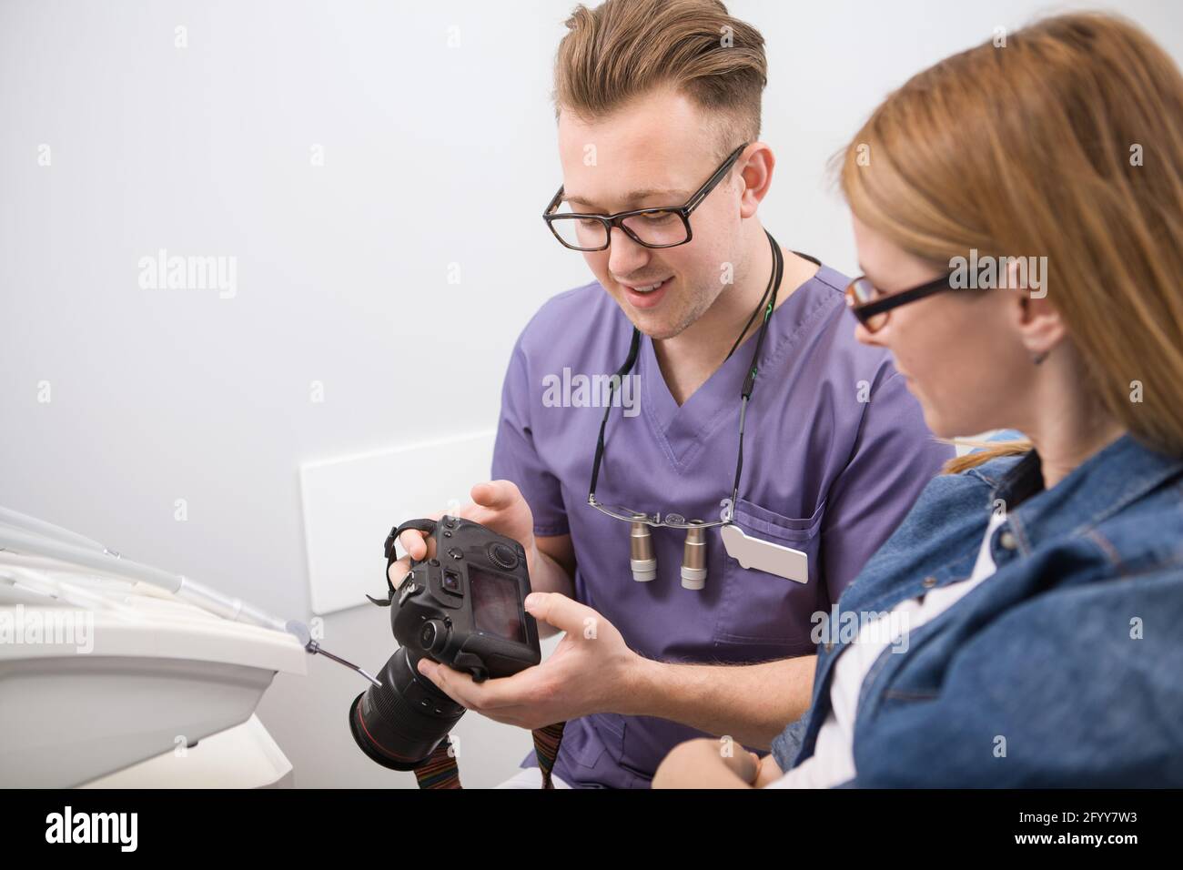 Männlicher Zahnarzt zeigt seine Patienten Fotos von ihren Zähnen danach Zahnbehandlung Stockfoto
