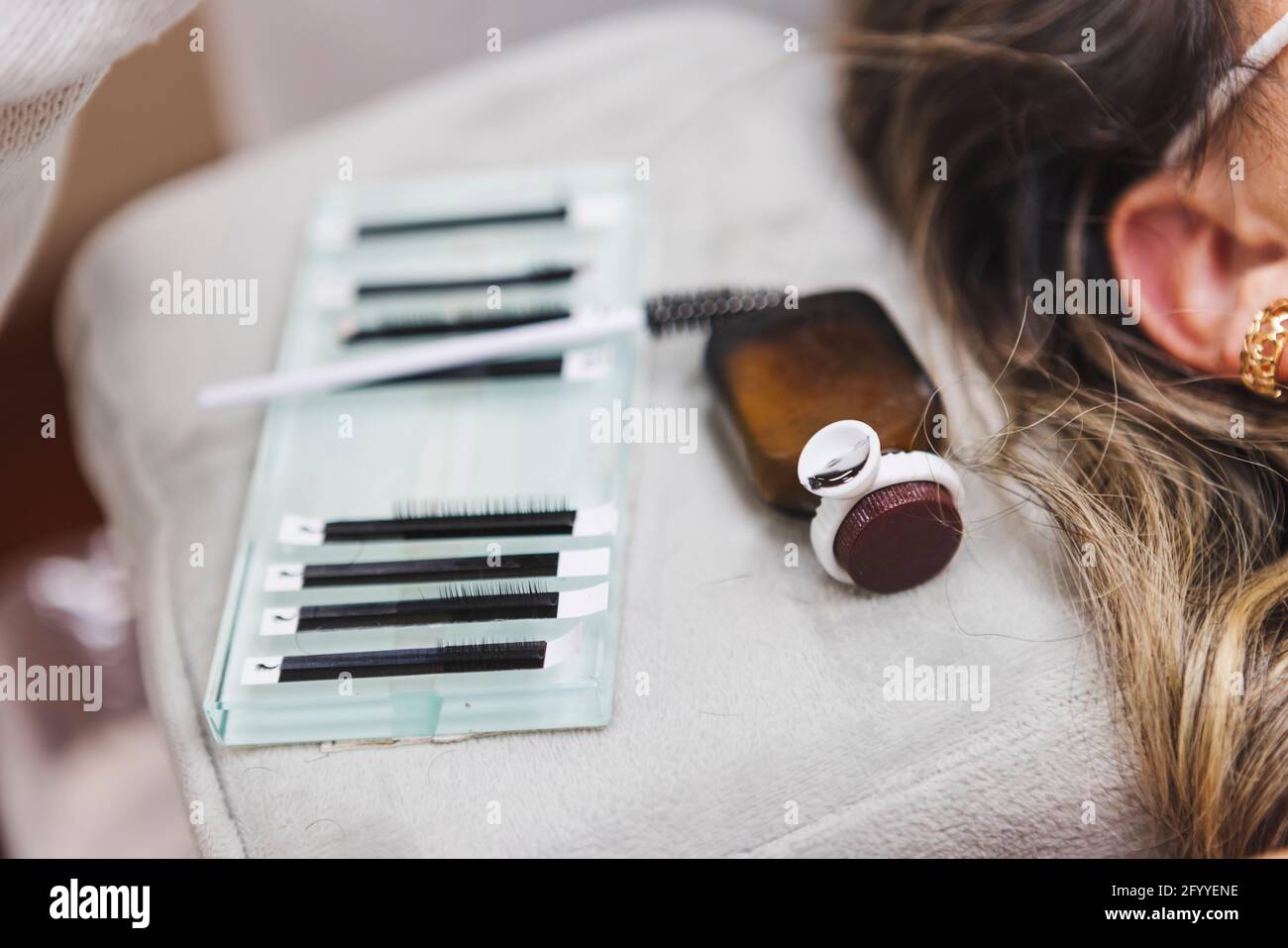 Crop anonyme Beauty-Techniker mit Pinzette unter Wimpern für Verlängerung gegen Frau während der Kosmetologie Verfahren Stockfoto