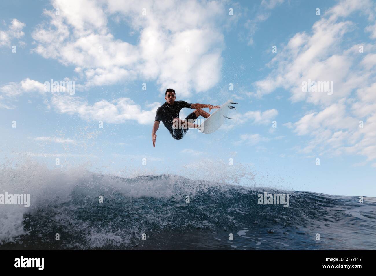 Junger Surfer auf dem Surfbrett übt Extremsport auf dem Meer aus Winken Sie unter bewölktem Himmel Stockfoto