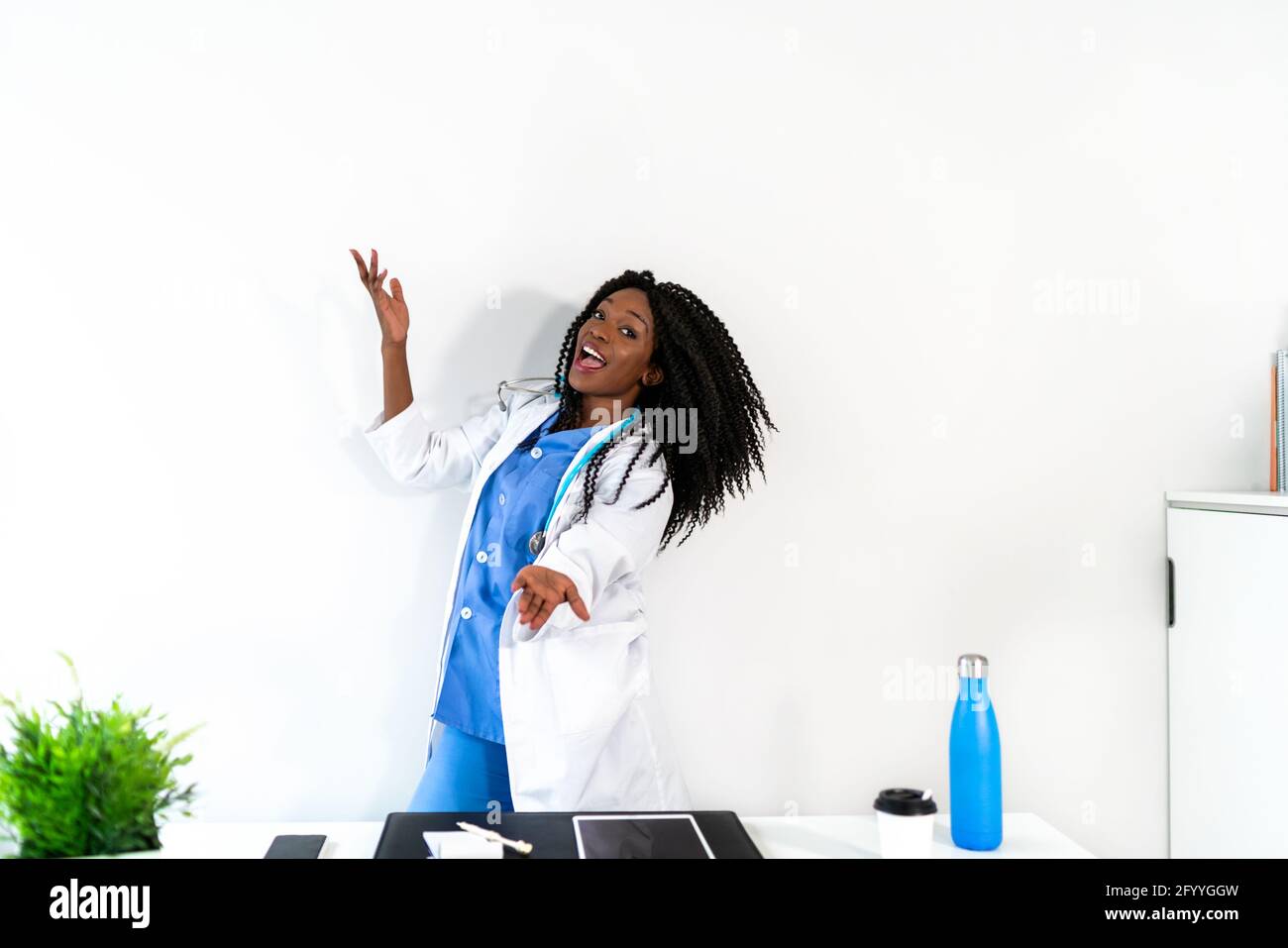 Afroamerikanische Frau in medizinischer Uniform tanzt in der Arztpraxis während der Pause Stockfoto
