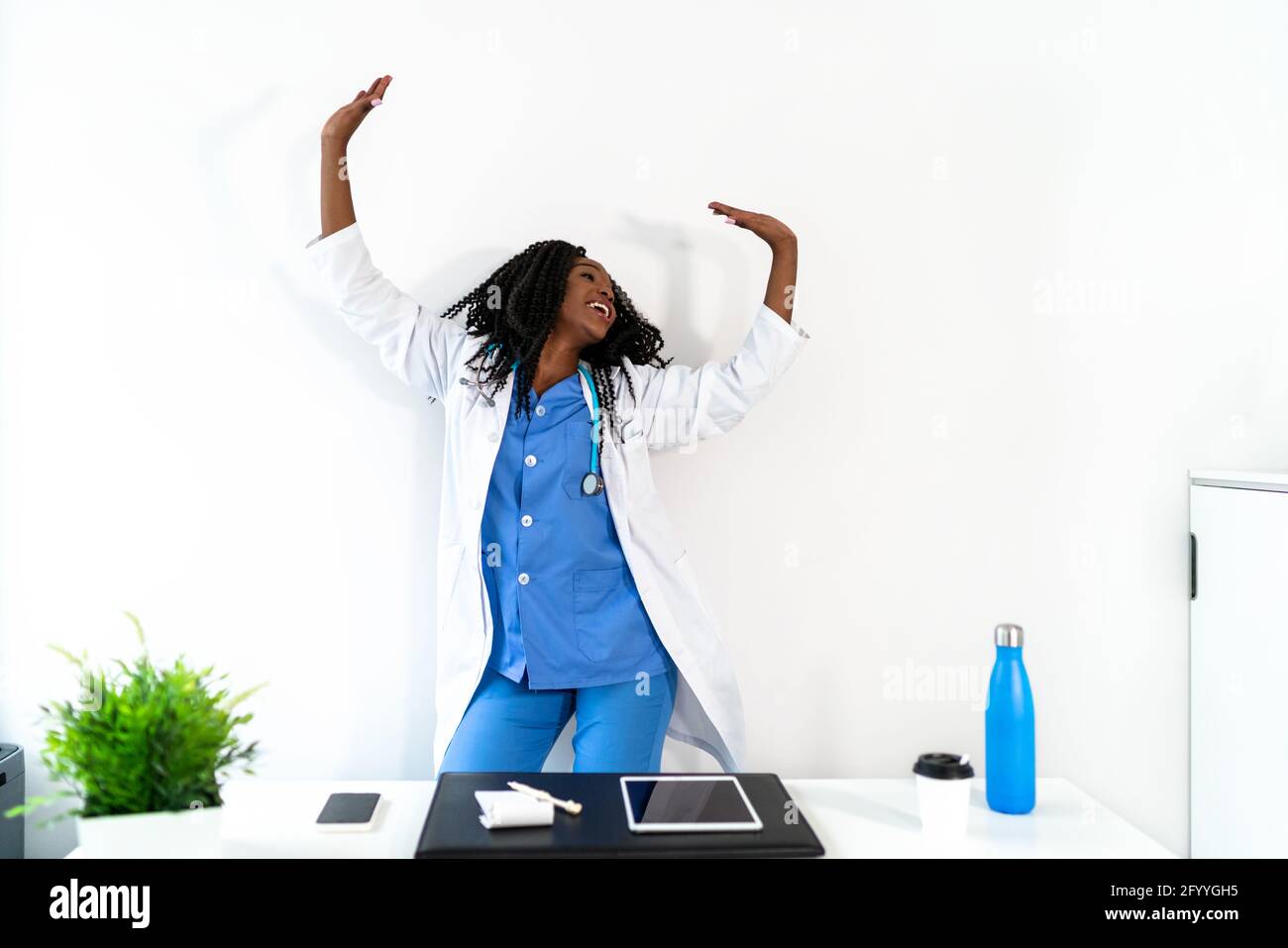Afroamerikanische Frau in medizinischer Uniform tanzt in der Arztpraxis während der Pause Stockfoto