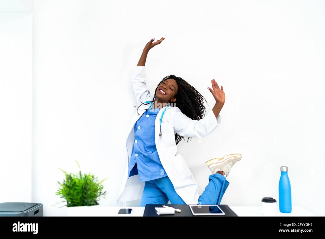 Afroamerikanische Frau in medizinischer Uniform tanzt in der Arztpraxis während der Pause Stockfoto