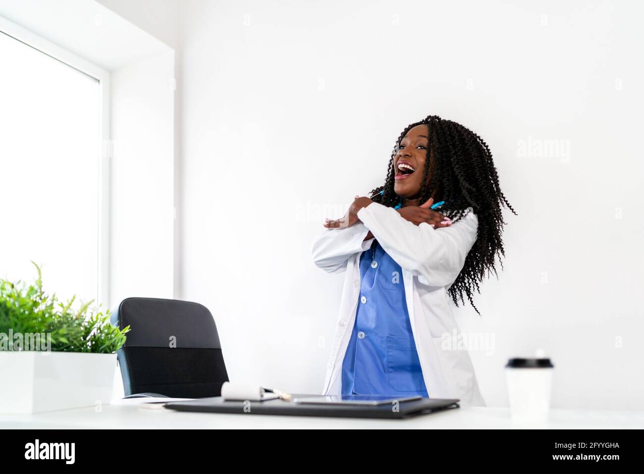 Afroamerikanische Frau in medizinischer Uniform tanzt in der Arztpraxis während der Pause Stockfoto