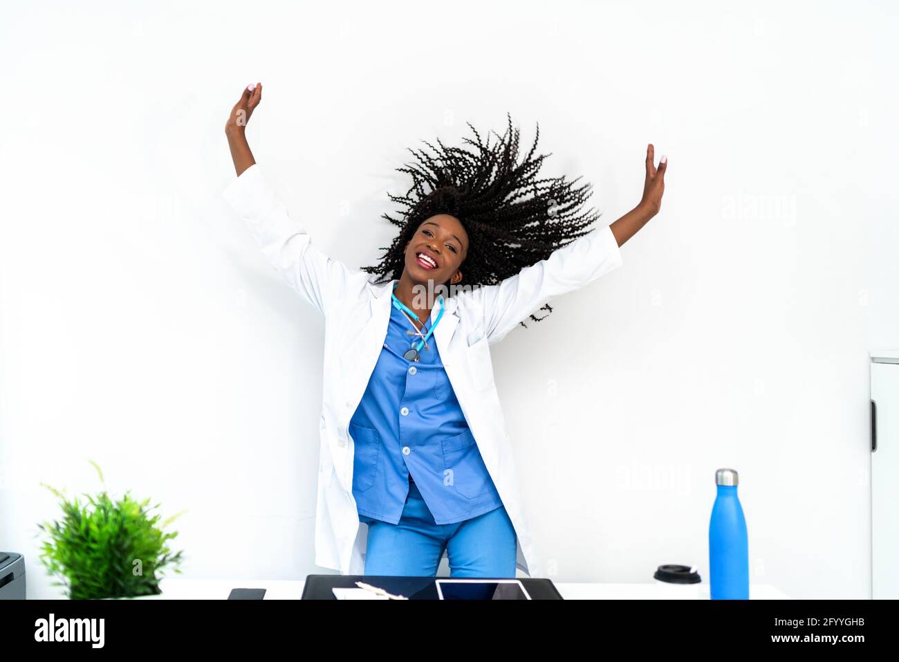 Afroamerikanische Frau in medizinischer Uniform tanzt in der Arztpraxis während der Pause Stockfoto