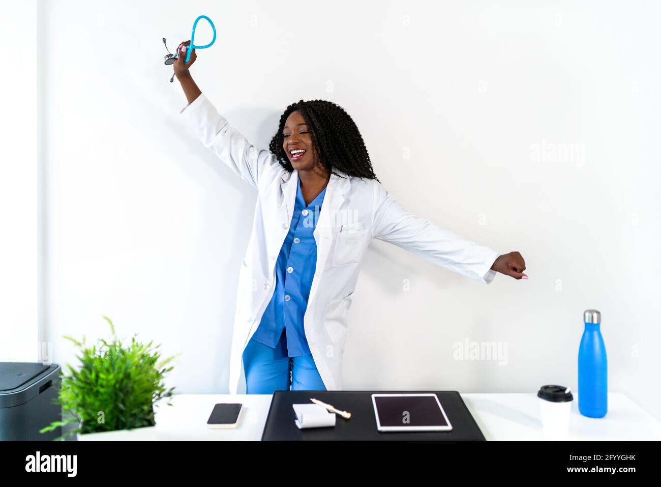 Afroamerikanische Frau in medizinischer Uniform tanzt in der Arztpraxis während der Pause Stockfoto