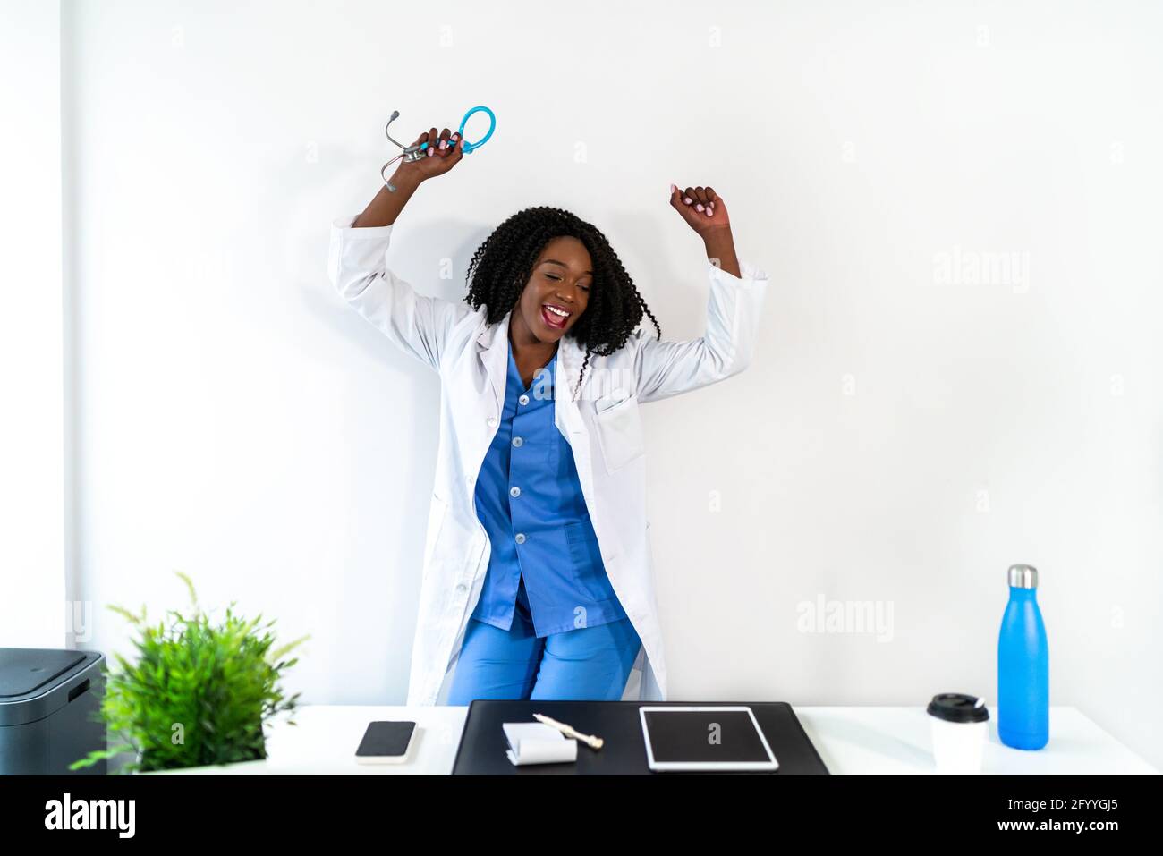 Afroamerikanische Frau in medizinischer Uniform tanzt in der Arztpraxis während der Pause Stockfoto