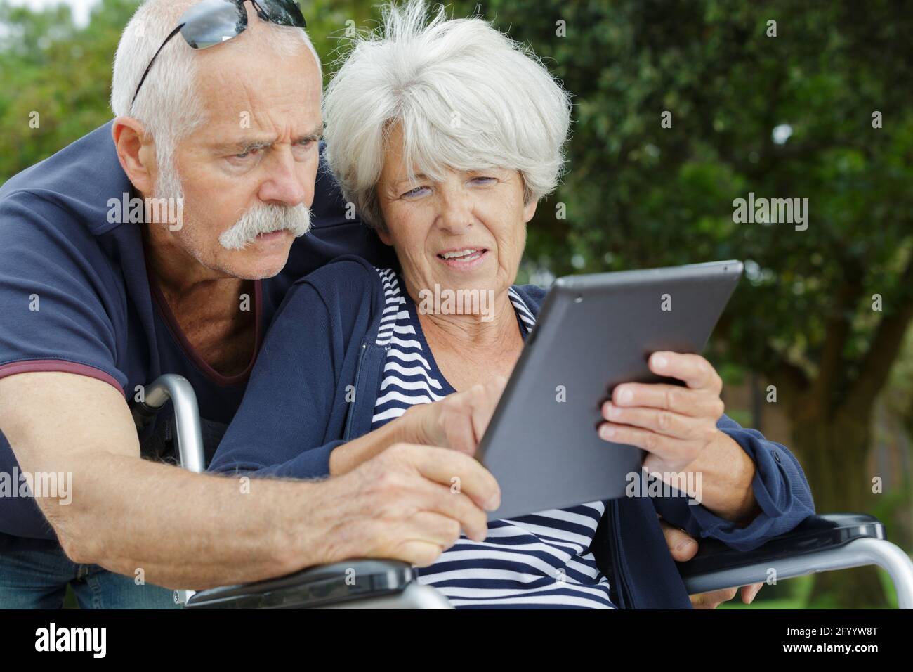 Frau im Rollstuhl mit Tablet im Park Stockfoto
