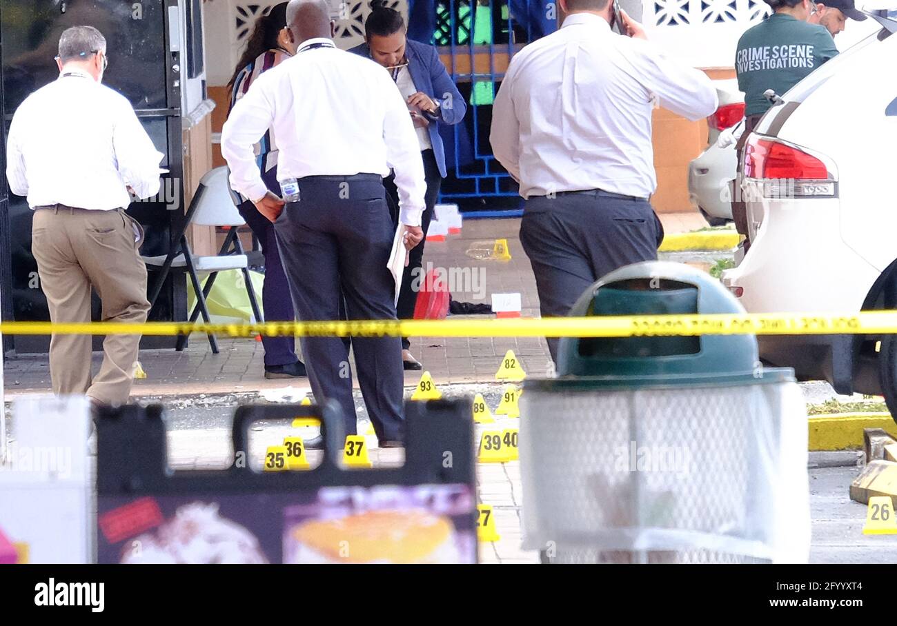 Ein Paar oder rote Schuhe sind auf einer der nicht identifizierten Leichen zu sehen, die mit gelben Planen bedeckt und von einem gelben Polizeistreifen-Band vor der El Mula Bankettsaal im Nordwesten von Miami-Dade County, in der Nähe von Hialeah, Florida, umgeben waren. Sonntag, 30. Mai, 2021. Nummerierte Zapfen sind an ausgegebenen Schalengehäusen von auf den Tatort abgefeuerten Kugeln zu sehen. Der Bankettsaal wurde für ein Konzert vermietet und in den frühen Morgenstunden fuhr ein SUV in den Saal, drei Schützen kamen heraus, töteten zwei und verletzten mindestens 20 weitere Konzertbesucher. Foto von Gary i Rothstein/UPI. Stockfoto