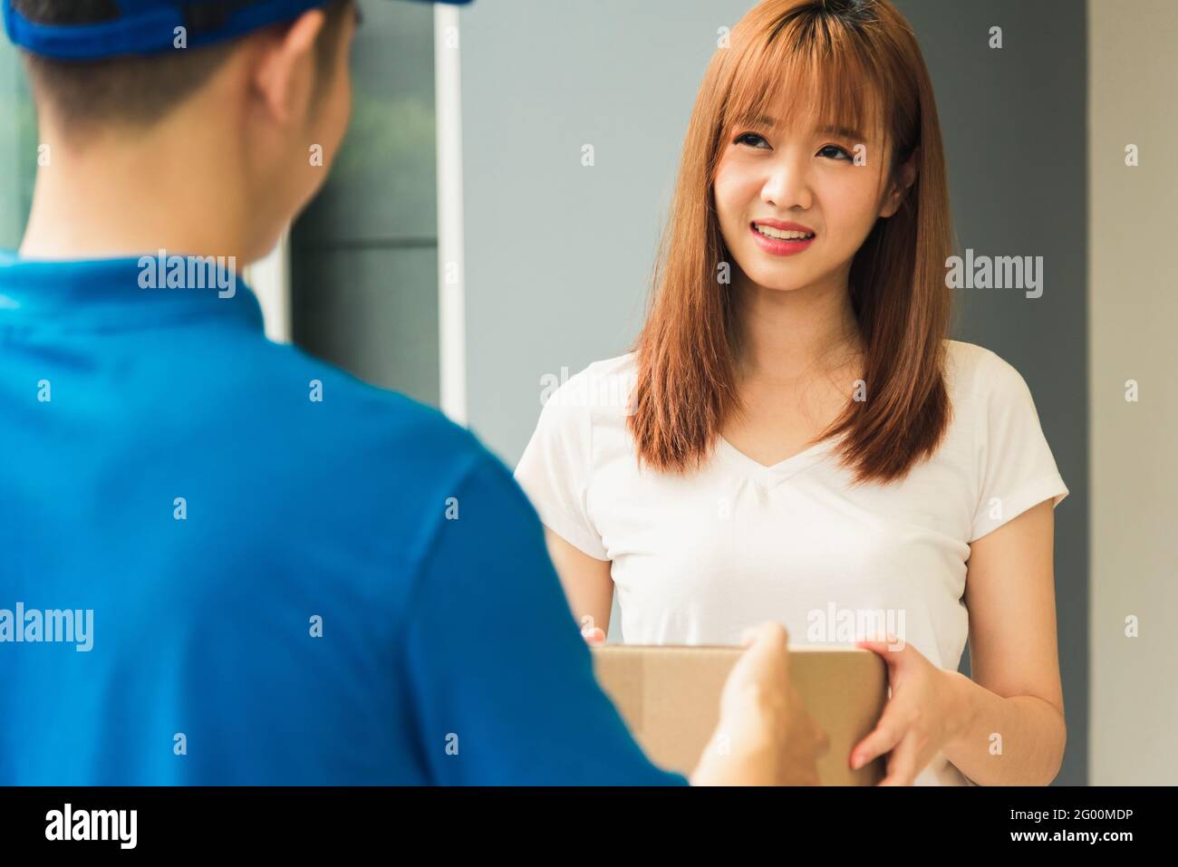 Asiatische junge Lieferung Mann Kurier in Uniform halten Paketpost Boxen Service Sendung Frau Kunde Empfang Paket von der Lieferung Vorne h Stockfoto