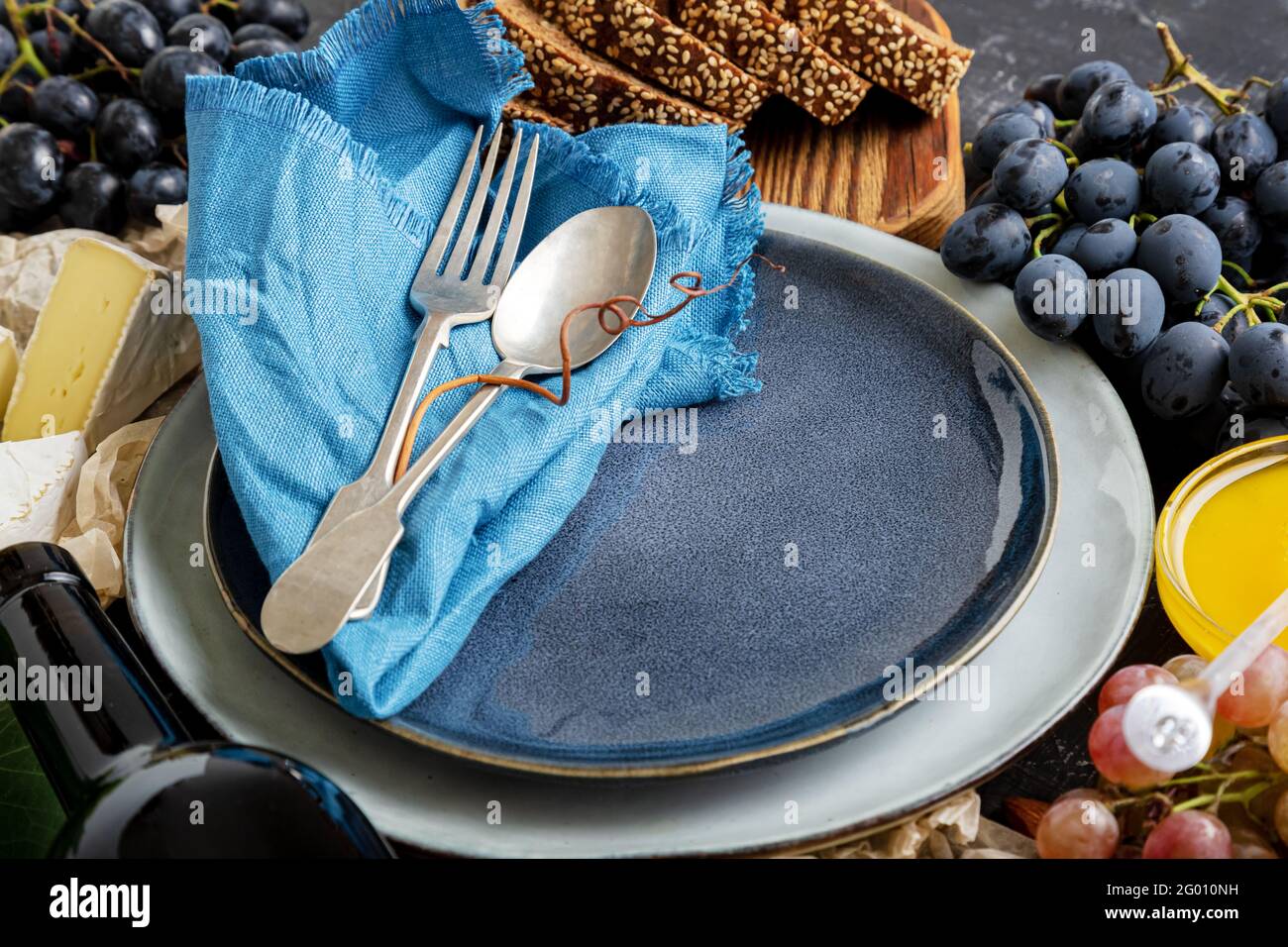 Leere Servierplatte mit Gabellöffel im Rahmen von Lebensmittelzutaten mediterrane Küche Gastronomie Vorspeise Snacks Trauben Käse Wein. Modell Stockfoto