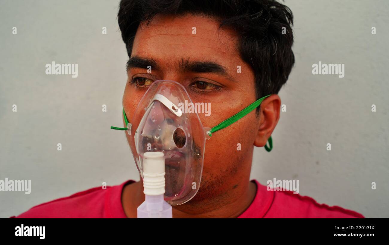 Porträt eines jungen Mannes mit Grippeinatmung zu Hause während des Lockdown in Rajasthan, Indien. Eine sitzende Person, Inhalation mit einer Verneblermaske zu Hause. Stockfoto