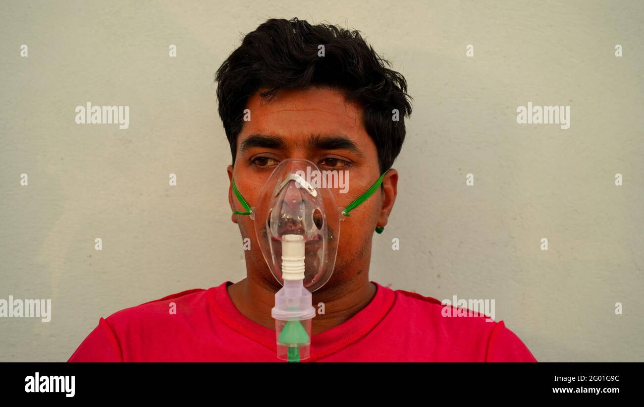 Ein indischer Mann mit Sauerstoffmaske auf dem Gesicht zu Hause während des Lockdown in Rajasthan, Indien. Junge Person sitzt und inhaliert reinen Sauerstoff für Coronavirus. Stockfoto