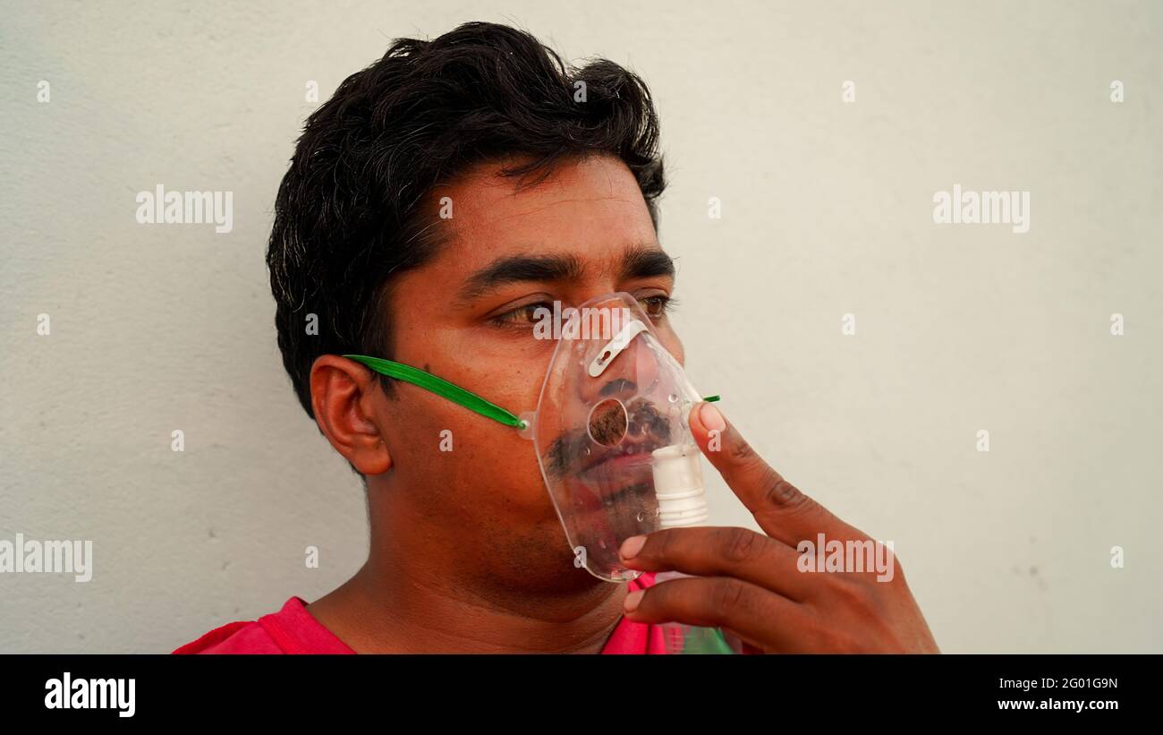 Porträt eines jungen Mannes mit Grippeinatmung zu Hause während des Lockdown in Rajasthan, Indien. Eine sitzende Person, Inhalation mit einer Verneblermaske zu Hause. Stockfoto