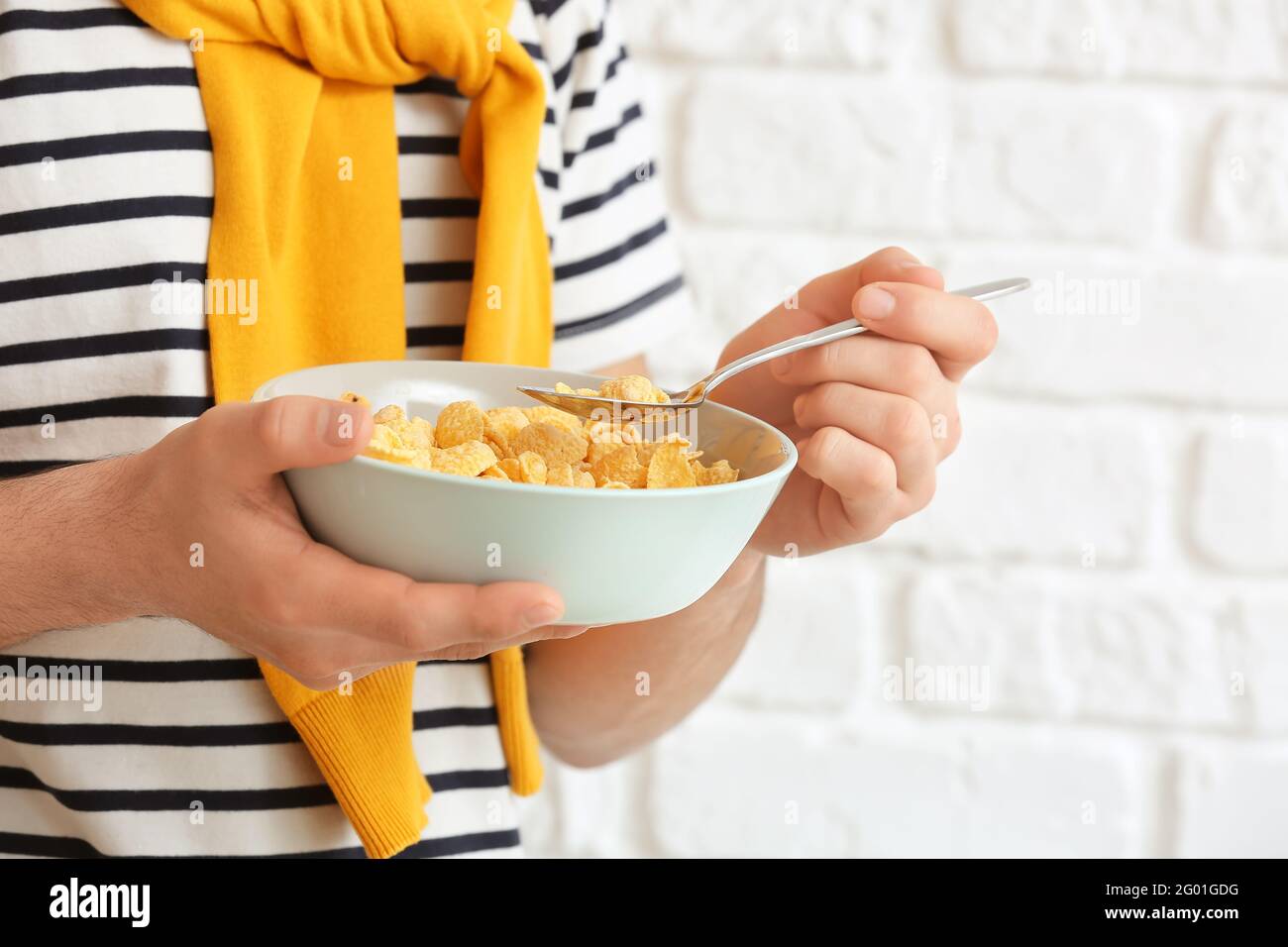 Junger Mann, der auf Backstein Cornflakes isst, Nahaufnahme Stockfoto