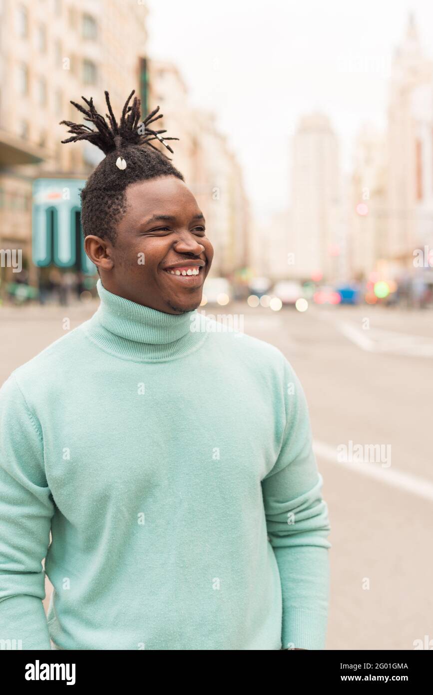 Junger schwarzer Mann mitten in der Stadt, lächelnd. Stockfoto