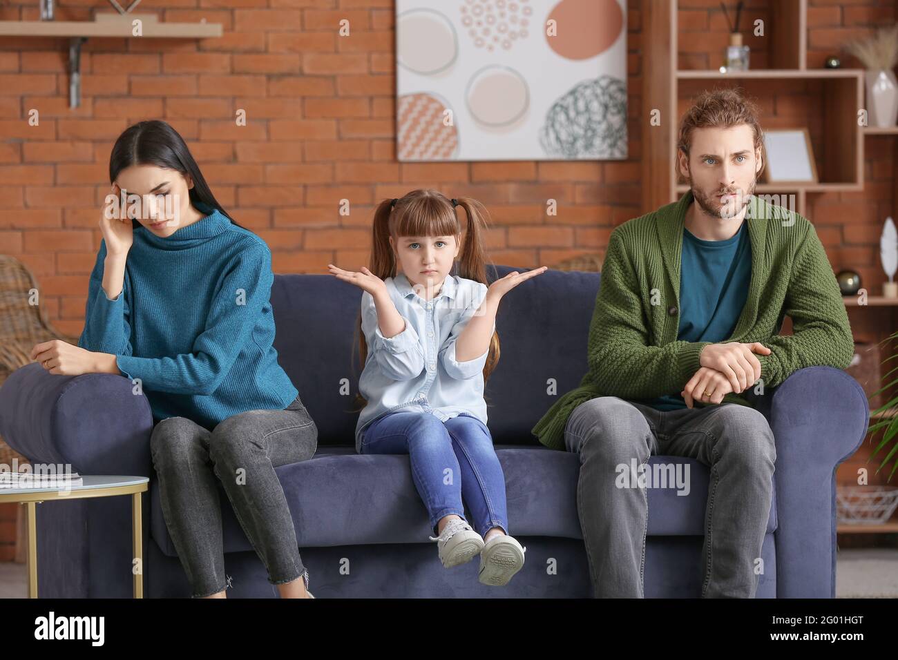 Trauriges kleines Mädchen und ihre Eltern nach dem Streit zu Hause Stockfoto
