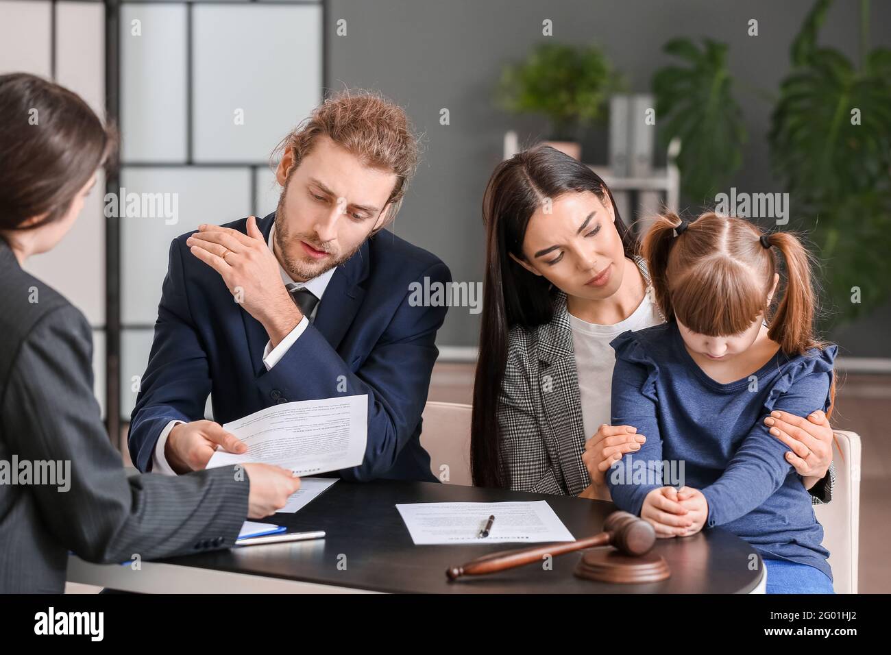Das junge Paar und ihre Tochter besuchen den Scheidungsanwalt im Büro Stockfoto