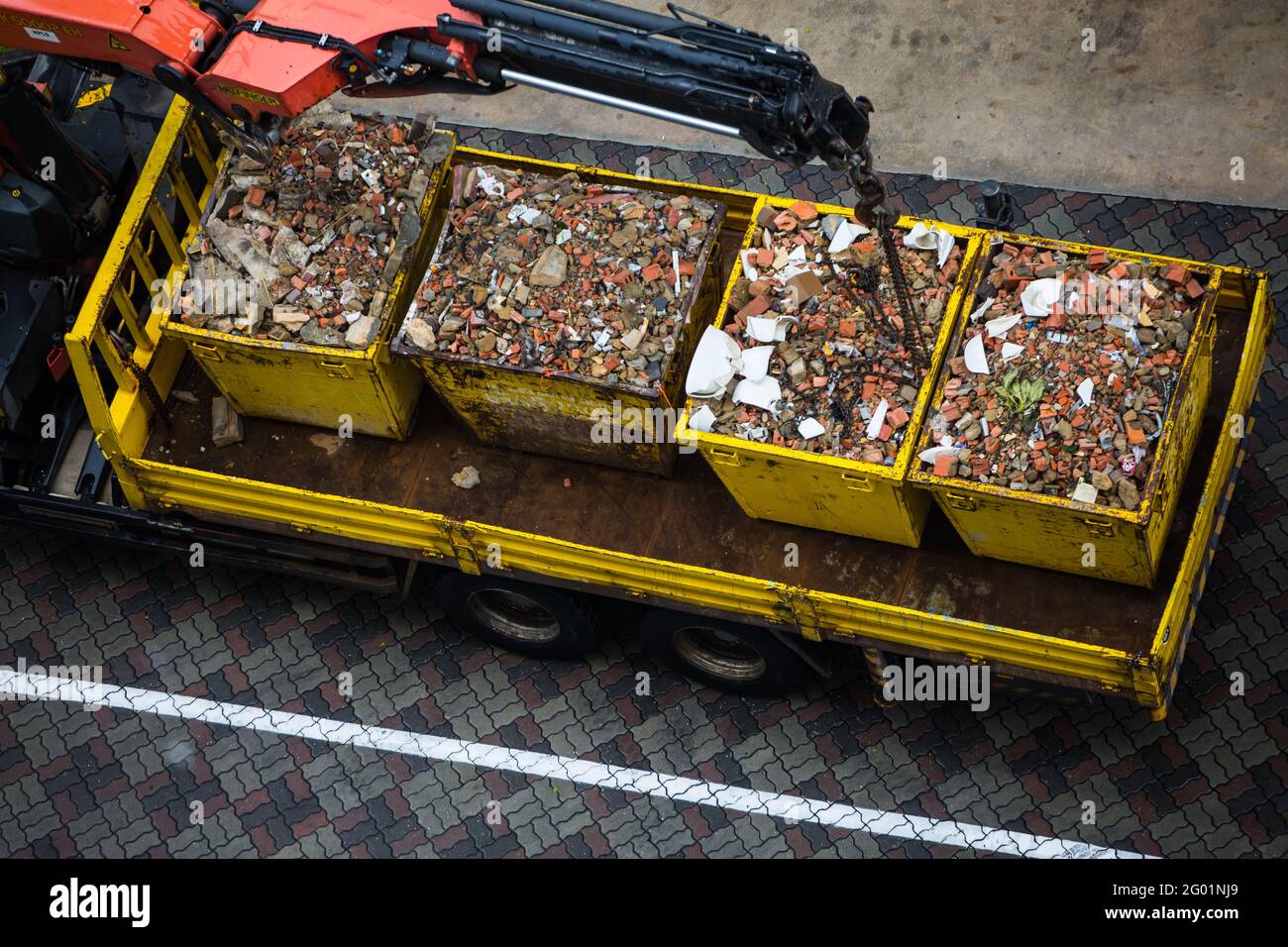 Auslegerkran senkt die riesigen Metallbehälter auf der Rückseite für den Transport ab. Stockfoto