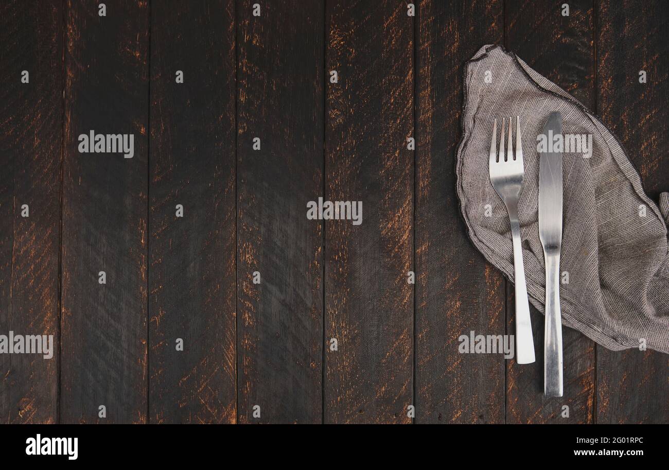 Besteck und Serviette auf Holzhintergrund, Draufsicht. Tischgestecke, Food-Konzept stilvolles Tischgestecke auf weißem Tisch mit silberner Gabel und Messer Stockfoto