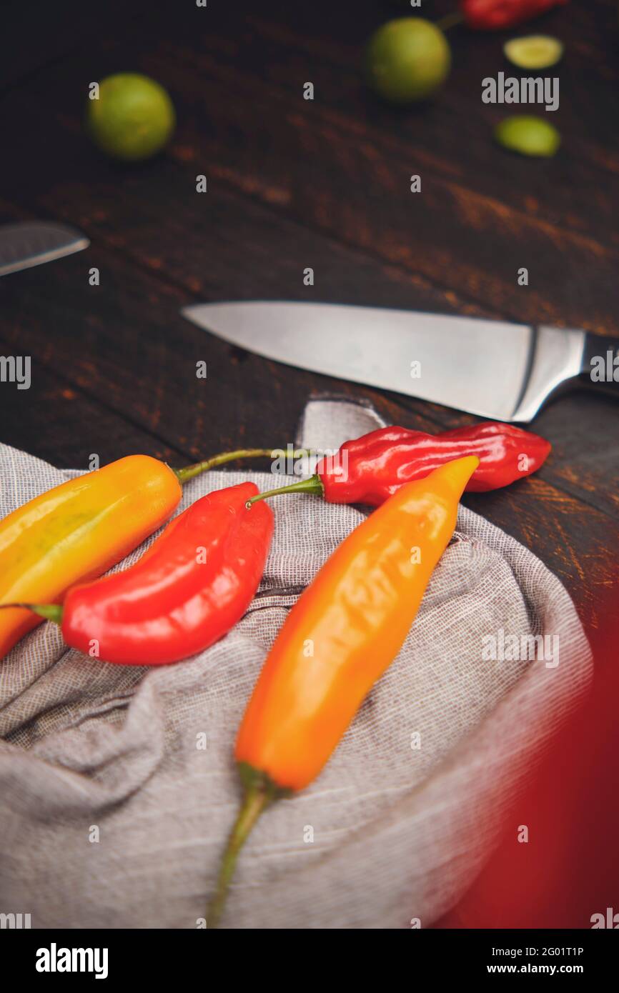 Peruanische Paprika mit anderen Zutaten auf Holztisch und Messer (Limo-Pfeffer, Ecabeche-Pfeffer und Zitrone) Draufsicht. Selektiver Fokus Stockfoto