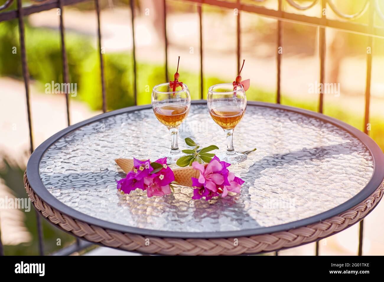 Sommeraperitif mit hausgemachten Cocktails mit rosa Blüten von Bougainvillea auf Glastisch. Erfrischungskonzept. Speicherplatz kopieren. Sommer grelle surreale Blumen und hausgemachte Getränke. Speicherplatz kopieren. Hohe Qualität Stockfoto