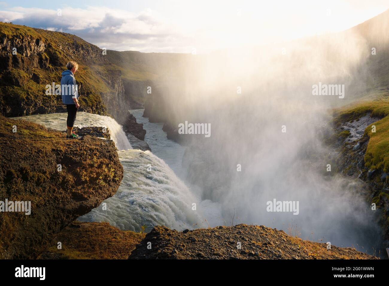 Junger Wanderer, der am Rande des Gullfoss Wasserfalls steht In Island Stockfoto