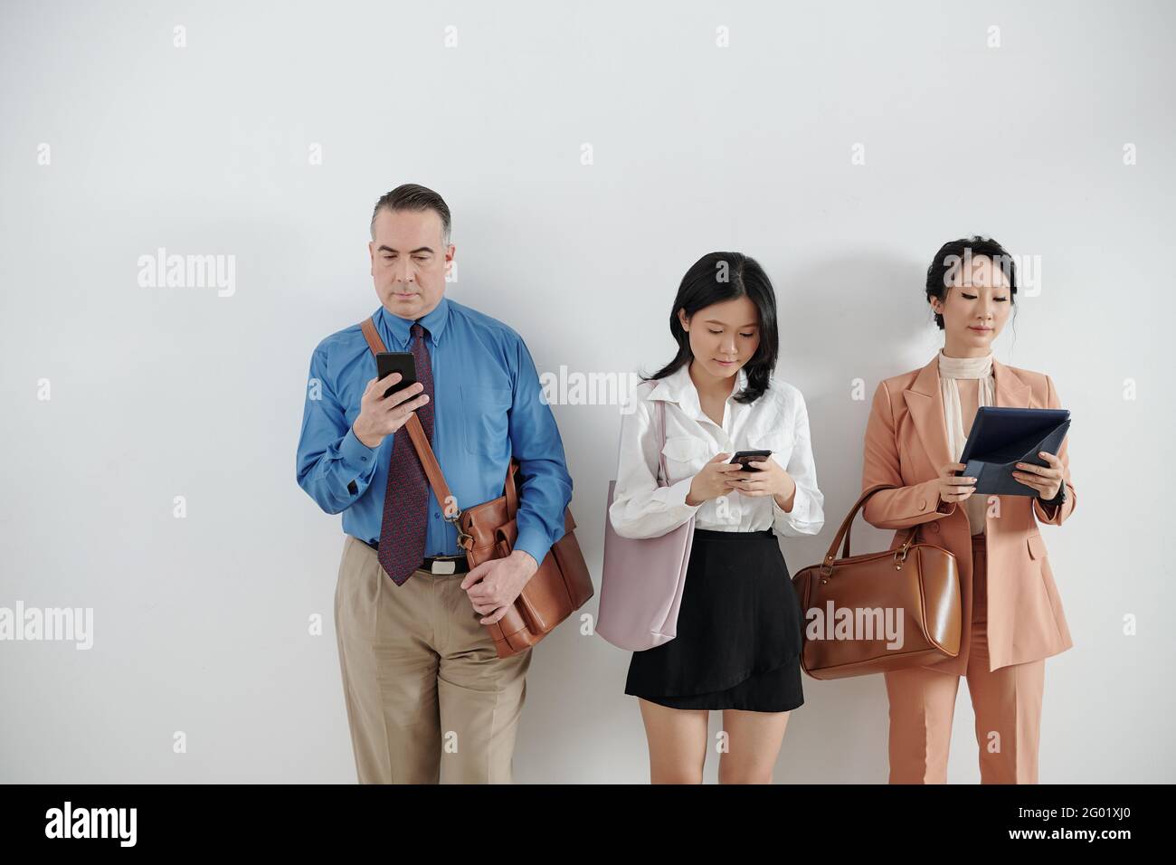 Bewerber stehen in der Warteschlange, warten auf Bewerbungsgespräche und checken Social Media auf Smartphones und Tablets Stockfoto