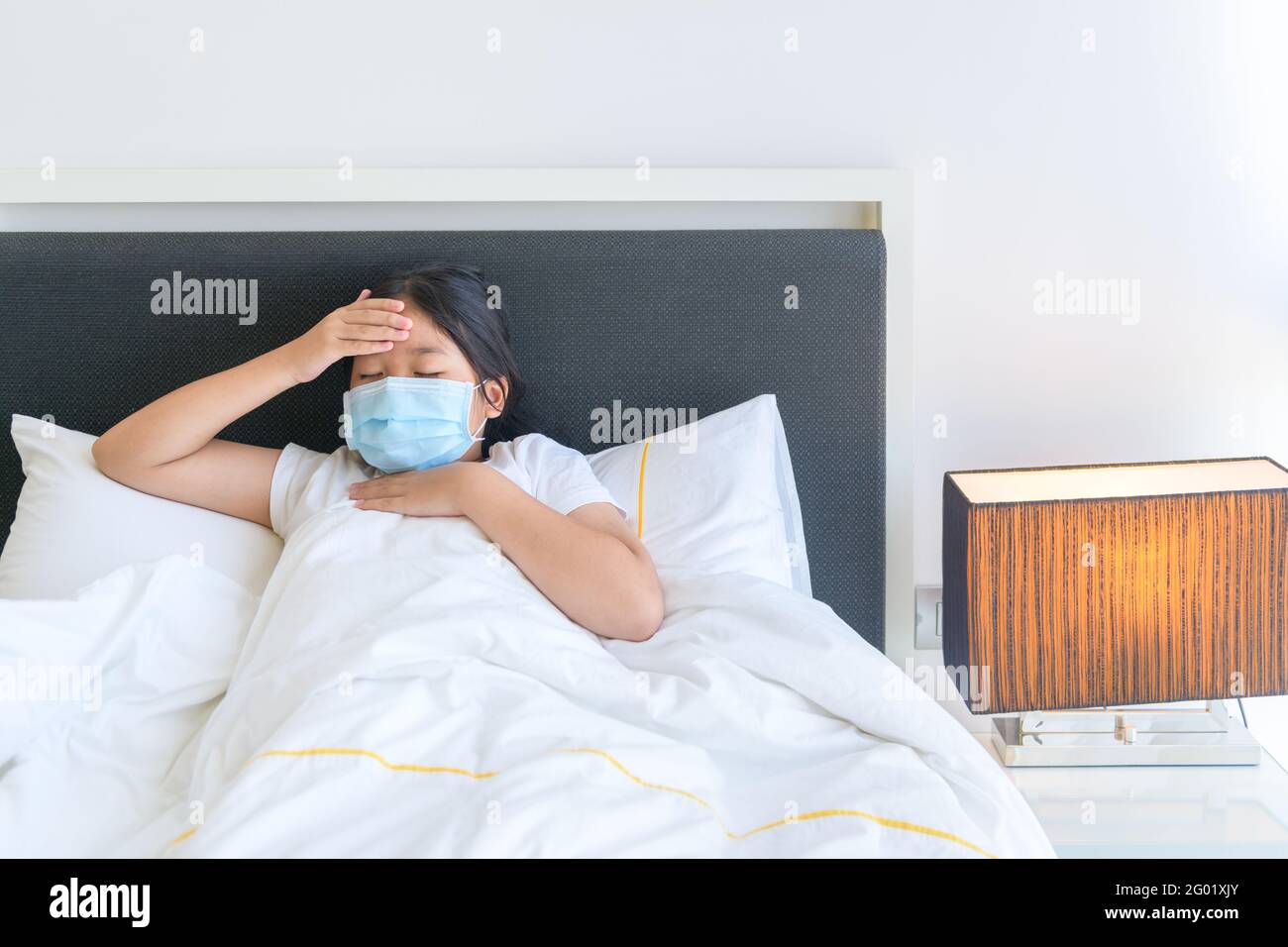 Unglücklicher kleiner Junge fühlt sich mit Viren oder Erkältungskrankheiten unwohl, hat Kopfschmerzen und misst die Körpertemperatur, die zu Hause im Bett liegt. Stockfoto