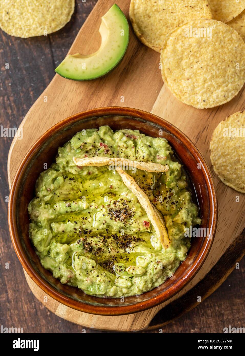 Schüssel mit Guacamole mit Tortilla-Chips auf Holzhintergrund Stockfoto