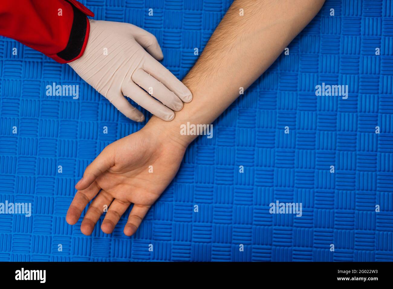 Der Arzt prüft den Puls der Geduld mit den Fingern, medizinische Untersuchung auf dem Tisch. Erste Hilfe Stockfoto
