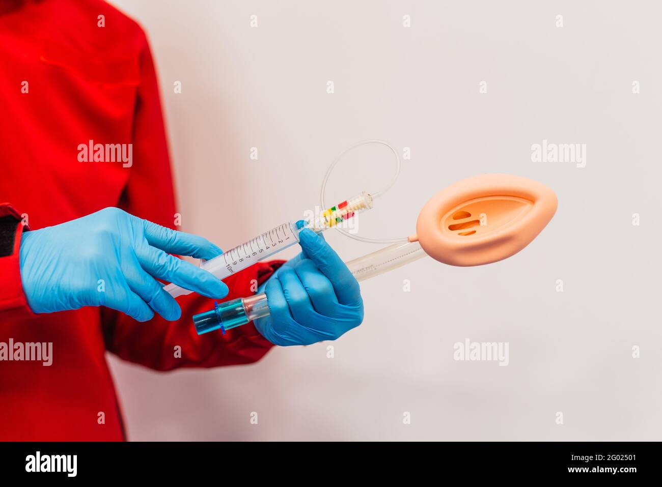 Ein Arzt in einer roten Uniform hält die Intubationsausrüstung, Nahaufnahme, einen weißen Hintergrund Stockfoto