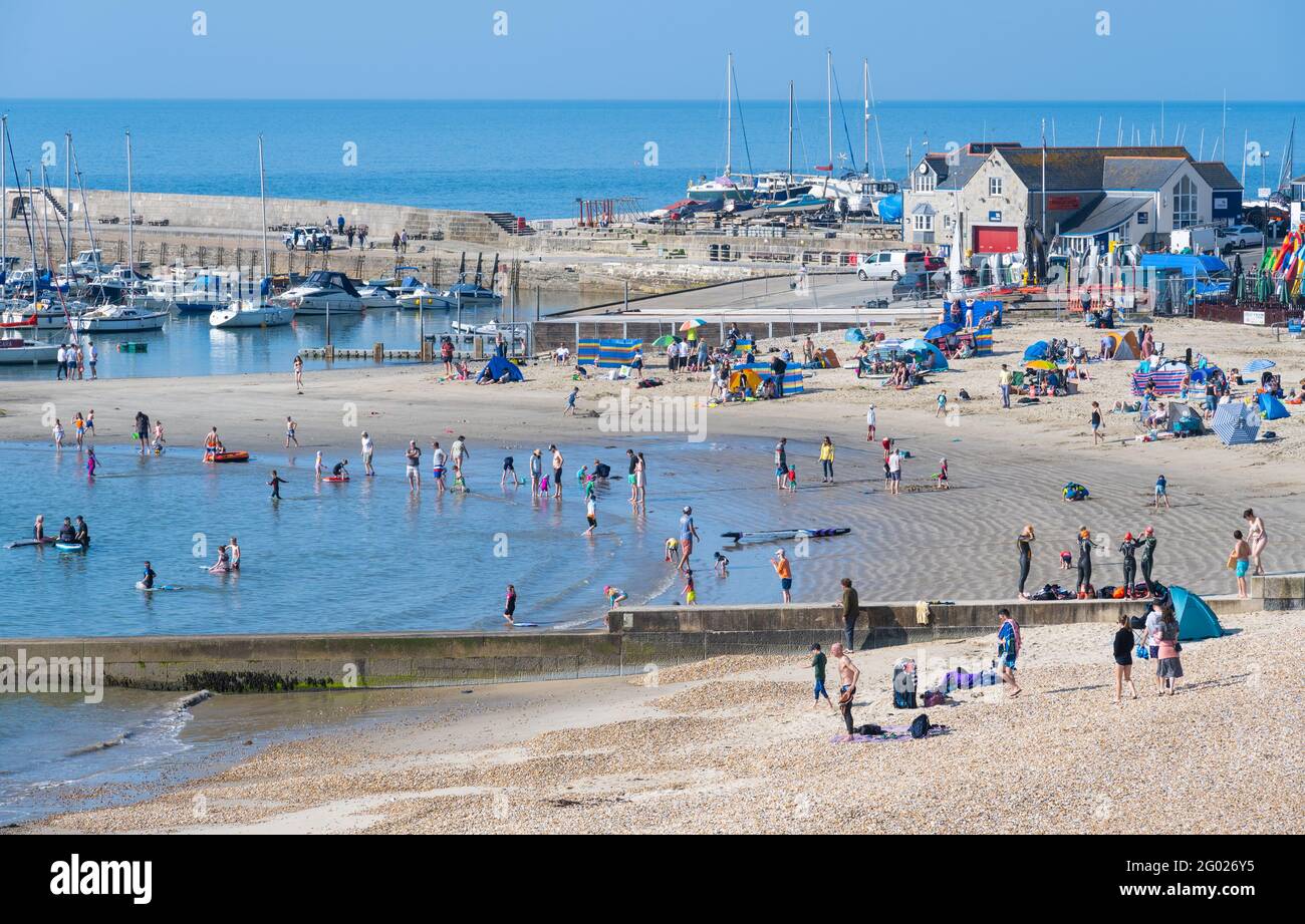 Lyme Regis, Dorset, Großbritannien. Mai 2021. UK Wetter: Lyme Regis wacht auf zu einem weiteren Tag mit herrlichem heißen Sonnenschein und klarem blauen Himmel am Feiertagsmontag. Der hübsche Strand füllte sich bereits um 9 Uhr, da eifrige Sonnenanbeter früh ankamen und sich einen guten Platz am beliebten Strand sicherten. Kredit: Celia McMahon/Alamy Live Nachrichten Stockfoto