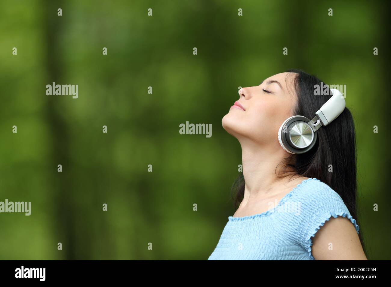 Asiatische Frau atmet frische Luft und hört Musik mit kabellosem Kabel Kopfhörer in einem Park Stockfoto