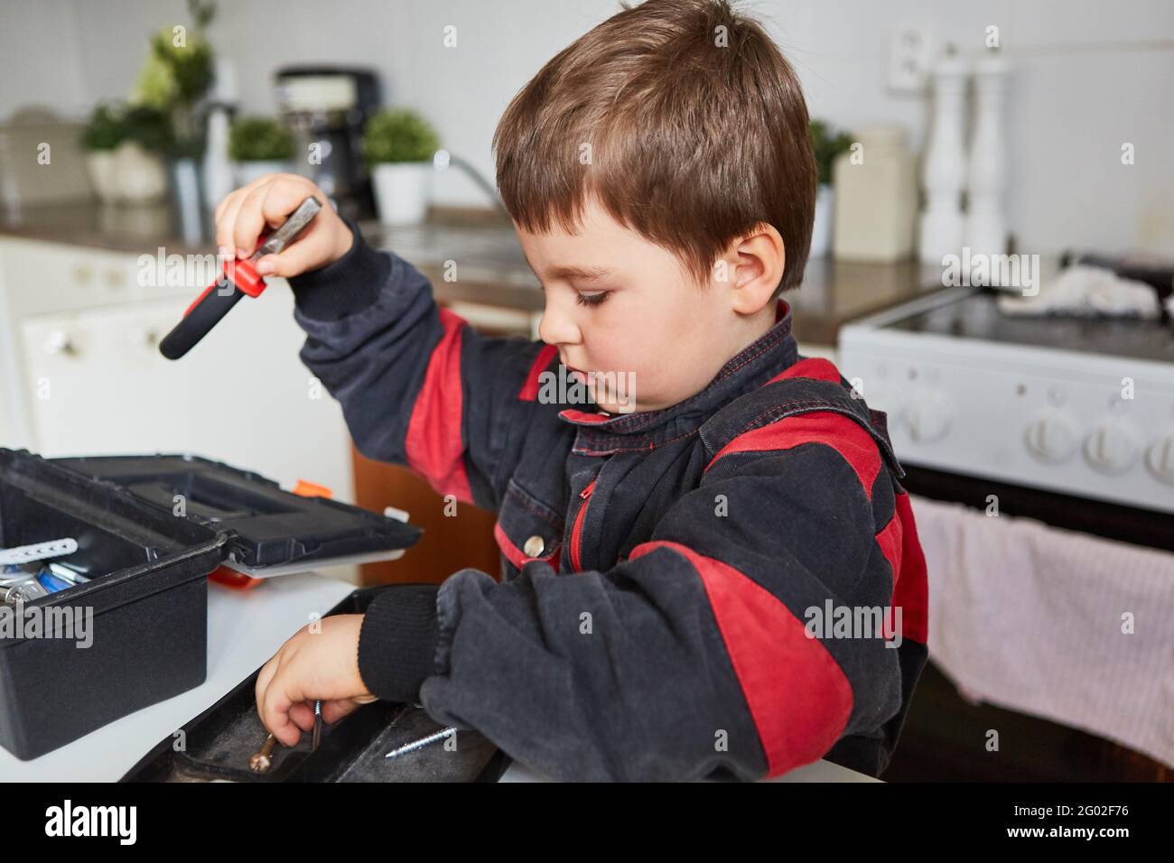 Das Kind spielt Handwerker oder Klempner und trägt den Werkzeugkasten auf Stockfoto