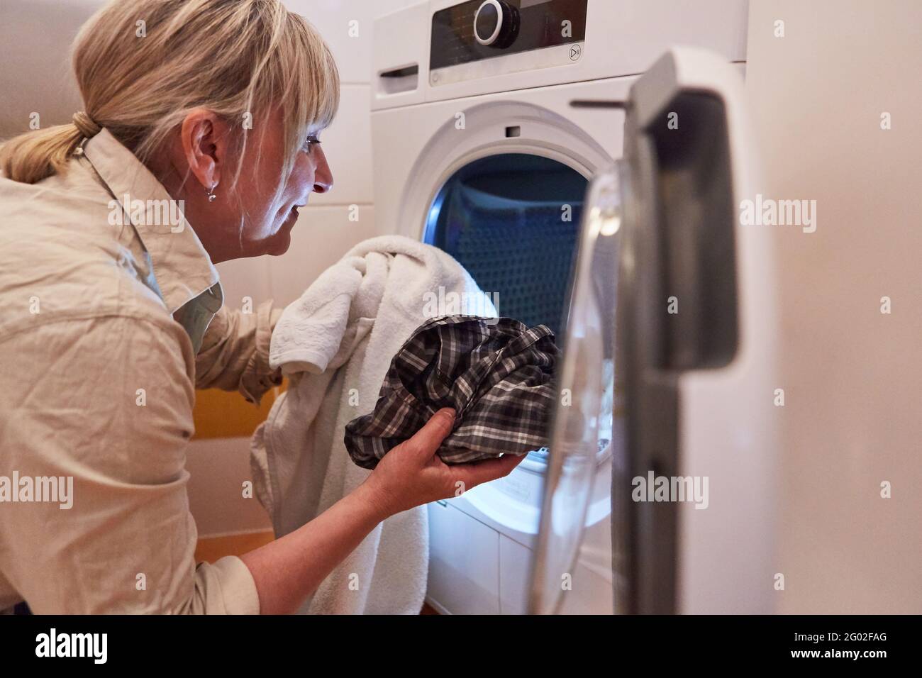Hausfrau vor dem Wäschetrockner oder der Waschmaschine Das Bad für Sauberkeit und Hygiene Stockfoto